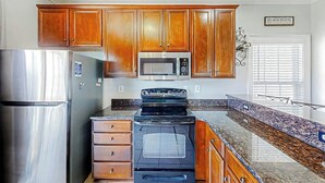 A kitchen with wooden cabinets, stainless steel appliances, and a granite countertop. - Pointe Marsh Unit 2414 (North Myrtle Beach)