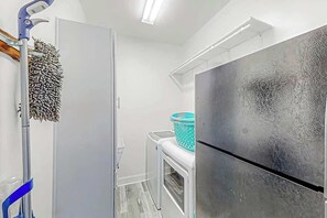 Eine kleine Küche mit Kühlschrank, Waschmaschine und Mopp.