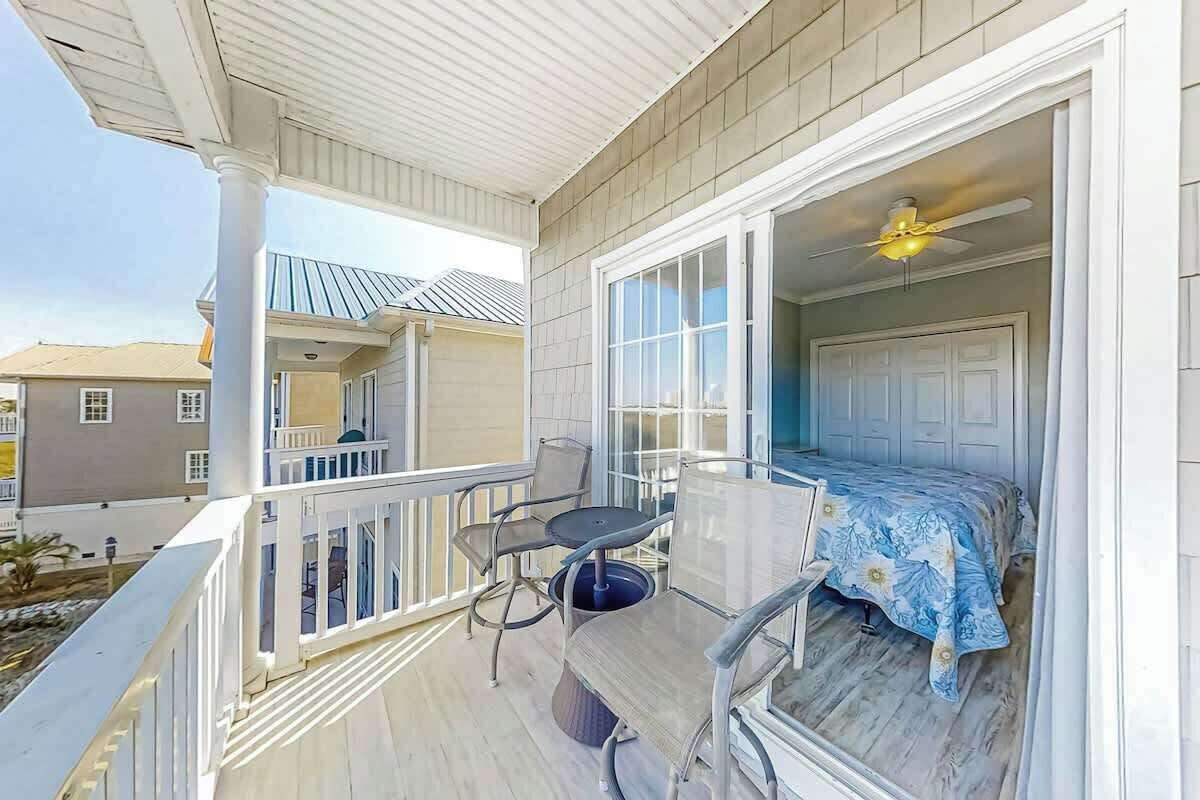 Un balcon avec une table et des chaises, un ventilateur de plafond et une vue sur les bâtiments voisins.