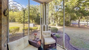 Zona de terrassa coberta amb moble de vimetes i vista a un jardí ben cuidat.