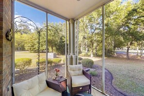 Ein überdachter Patio-Bereich mit Korbmöbeln und Blick auf einen angelegten Garten.
