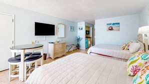 Una habitación con una cama, un escritorio con una silla, un televisor y una puerta.