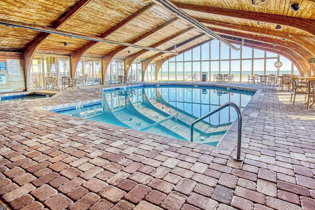 Une piscine intérieure avec un sol en briques et un plafond en bois.