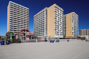 Ein Strandhotel mit mehreren Hochhäusern, einer Promenade und einem Restaurant direkt am Strand.