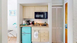 Una cocina compacta con microondas, pileta y un refrigerador pequeño.