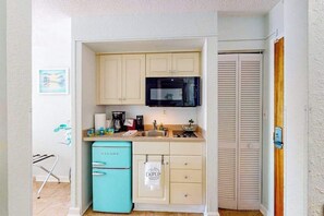 Eine kompakte Küche mit Mikrowelle, Spüle und kleinem Kühlschrank.