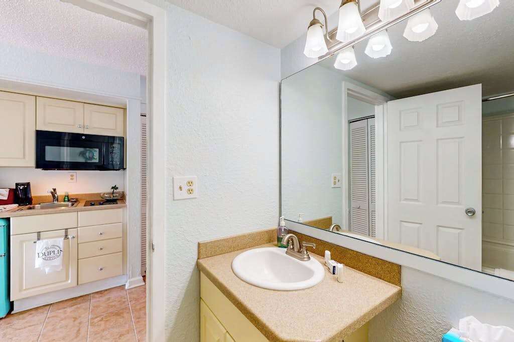 A bathroom with a sink, mirror, and overhead lights.