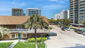 Un hôtel composé d’un bâtiment principal, d’un parking et entouré d’immeubles de grande hauteur.