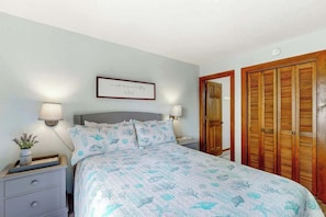 A bedroom with a bed, bedside tables, a wall-mounted lamp, a framed quote, and wooden closets. - Shipwatch Pointe I E-308 (Myrtle Beach)