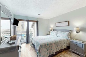 A hotel room with a bed, bedside lamps, a desk, and a window with curtains. - Shipwatch Pointe I E-308 (Myrtle Beach)