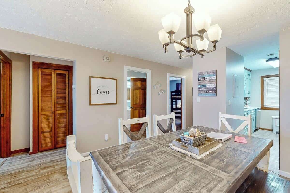 A dining area with a wooden table, white chairs, and a chandelier.