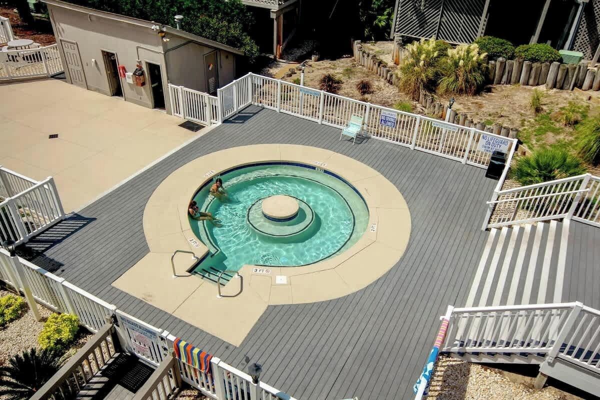 Piscina en la azotea con diseño circular, rodeada por una terraza con barandillas.