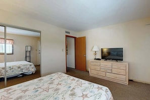 Ein Hotelzimmer mit Bett, Fernseher, Kommode und Spiegel.