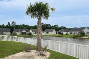 A residential area with a white picket fence, a palm tree, and houses with grey roofs. - Turtle Cove Beach Retreat (Myrtle Beach)
