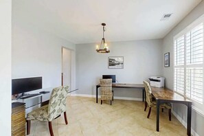 Uma sala de jantar com mesa, cadeiras, televisão e impressora.