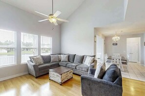 Ein geräumiges Wohnzimmer mit einem Ecksofa, einem Couchtisch und einem Essbereich mit Tisch und Stühlen.
