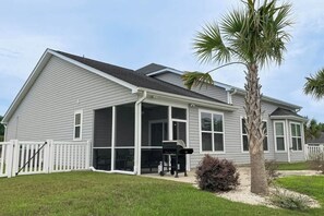 A single-story house with a covered porch, a screened window, and a palm tree in the yard. - Turtle Cove Beach Retreat (Myrtle Beach)