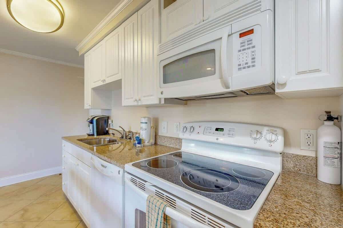 A kitchen with white cabinets, a microwave, a stove, and a coffee maker.