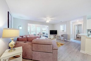 A spacious living area with a sofa, a television, and a dining area. - Seascape Beach Retreat (Murrells Inlet)