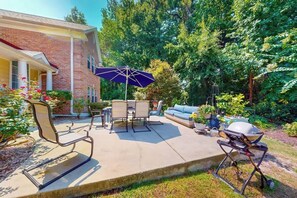 Eine Terrasse im Freien mit Grill, Sitzgelegenheiten und einem überdachten Tisch.