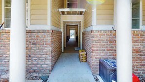 A corridor with brick walls and a concrete floor, leading to a door at the end. - Seascape Beach Retreat (Murrells Inlet)