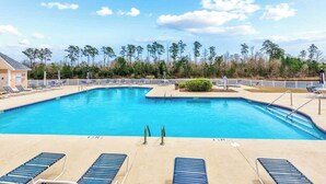 A swimming pool with lounge chairs and a view of trees. - Anchors Away Unit 7G (Myrtle Beach)
