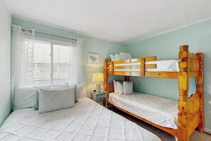 A bedroom with two beds, a window with blinds, a bedside table with a lamp, and a wall-mounted picture. - Steps to the Beach Home (North Myrtle Beach)