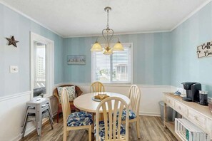 A dining area with a round table, chairs, and a hanging light fixture. - Steps to the Beach Home (North Myrtle Beach)