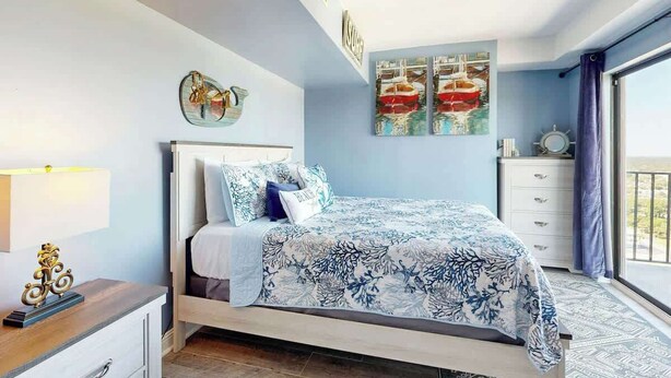 A bedroom with a bed, a dresser, a nightstand, and a window with a view. - Sunrise at the Beach (Myrtle Beach)