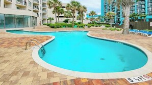 A swimming pool with a tiled deck, surrounded by a multi-story building with balconies. - Sunrise at the Beach (Myrtle Beach)