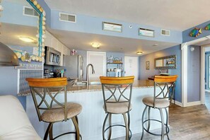 A kitchen with a central island, bar stools, and a microwave. - Sunrise at the Beach (Myrtle Beach)