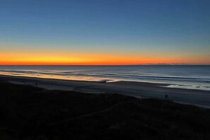 A coastal sunset view with a road leading to the beach. - Palmetto Dunes Unit 303 (North Myrtle Beach)