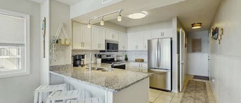 A modern kitchen with white cabinets, a granite countertop, and stainless steel appliances.