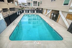 A rectangular swimming pool with a black fence, a lifeguard chair, and a sign indicating a depth of 8 feet. - Palmetto Dunes Unit 303 (North Myrtle Beach)