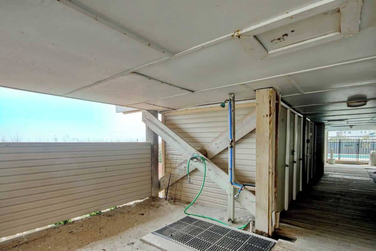A construction site with exposed wooden beams, a metal grate, and construction materials.