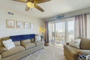 A living room with a sofa, a chair, a ceiling fan, and a view through a glass door to the outside. - Palmetto Dunes Unit 303 (North Myrtle Beach)