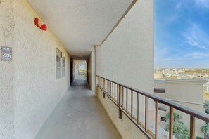 Ein Korridor mit Balkon, Brandmelder und Blick auf Gebäude.