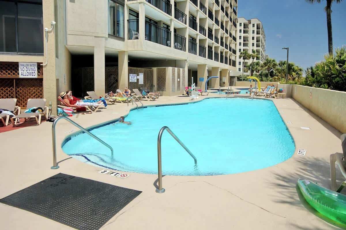 Piscina con sillones de descanso y un letrero que indica agua poco profunda.