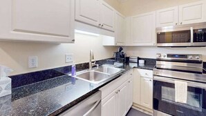 A modern kitchen with white cabinets, stainless steel appliances, and a granite countertop. - Savannah Shores Unit 12 (Myrtle Beach)