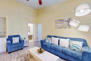 Ein Wohnzimmer mit einem blauen Sofa, einem Couchtisch und einem Gemälde an der Wand.