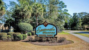 A sign for Savannah Shores Condominium Community with a landscaped area and trees. - Savannah Shores Unit 12 (Myrtle Beach)