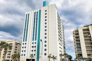 A tall hotel with multiple floors, a prominent vertical sign, and a blue cylindrical structure on top. - This is It 2 BR Condo (North Myrtle Beach)