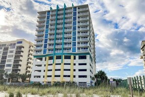 A multi-story hotel with balconies, a beach view, and a clear sky. - This is It 2 BR Condo (North Myrtle Beach)