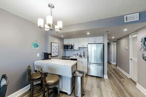 A modern kitchen with a central island, stainless steel appliances, and a chandelier. - This is It 2 BR Condo (North Myrtle Beach)