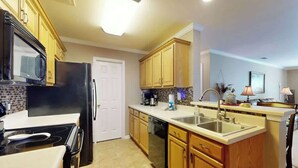 A kitchen with wooden cabinets, a black refrigerator, a microwave, a stove, and a dishwasher. - Sterling Pointe 120-A at Wachesaw III (Murrells Inlet)