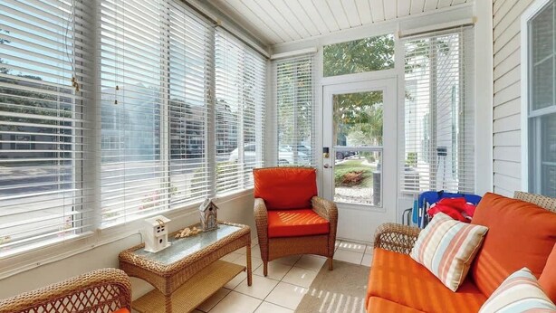 A sunroom with a wicker sofa, a chair, and a small table. - Sterling Pointe 120-A at Wachesaw III (Murrells Inlet)