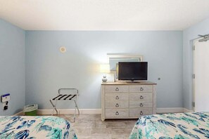 A hotel room with two beds, a dresser with a television, a lamp, and a small chair. - Bay Watch Resort 1103 (North Myrtle Beach)