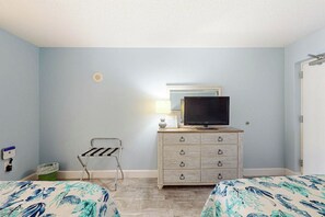 A room with two beds, a dresser with a television, a lamp, and a small chair. - Bay Watch Resort 1103 (North Myrtle Beach)