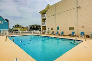 An indoor swimming pool with a pool ladder, lounge chairs, and a building with balconies. - Coastal Tranquility Retreat (North Myrtle Beach)
