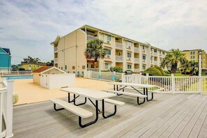 Ein mehrstöckiges Hotel mit Balkonen, einem Poolbereich und Picknicktischen auf einer Terrasse.
